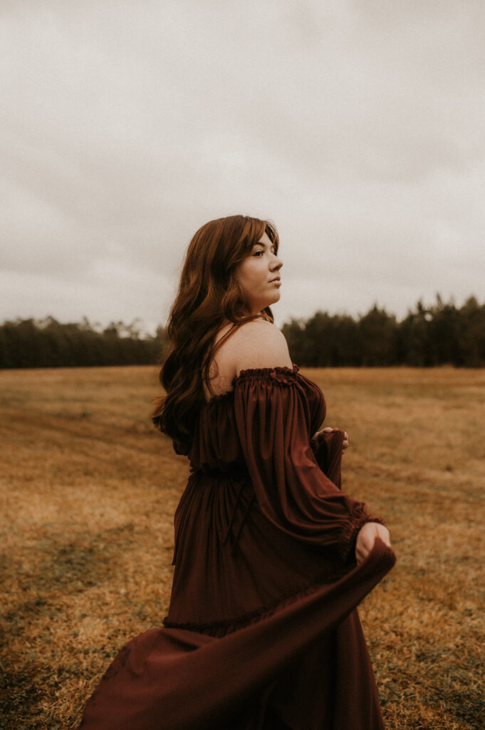 Portrait of woman in a beautiful maroon dress flowing in the wind