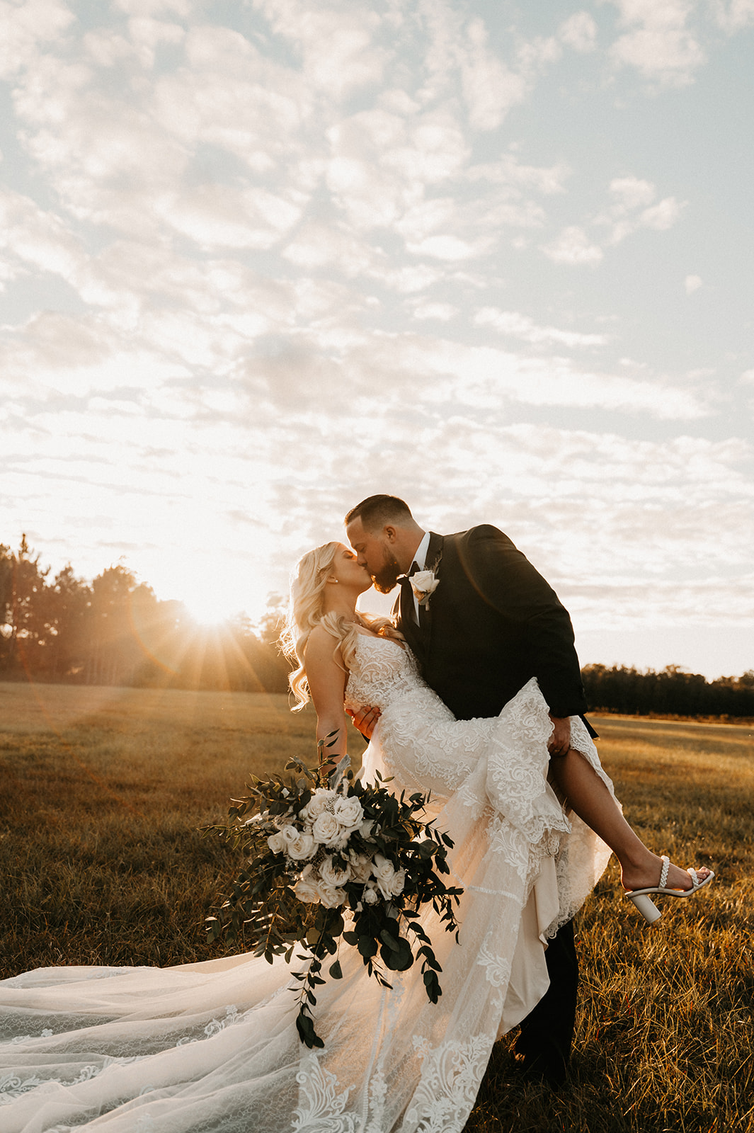 beautiful couple kissing before their ceremony with the sun in the background