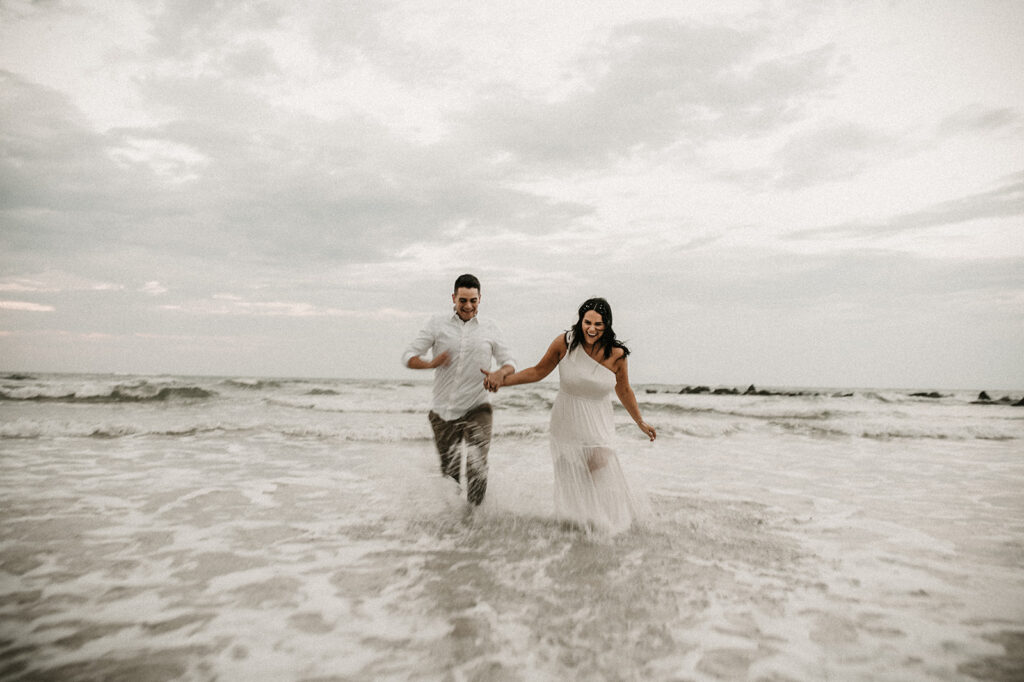 gorgeous couple running at the beach during their engagement session