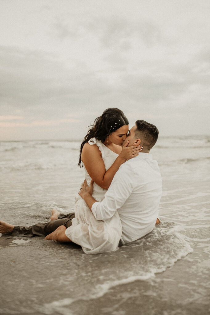 couple kissing with the beach in the background 