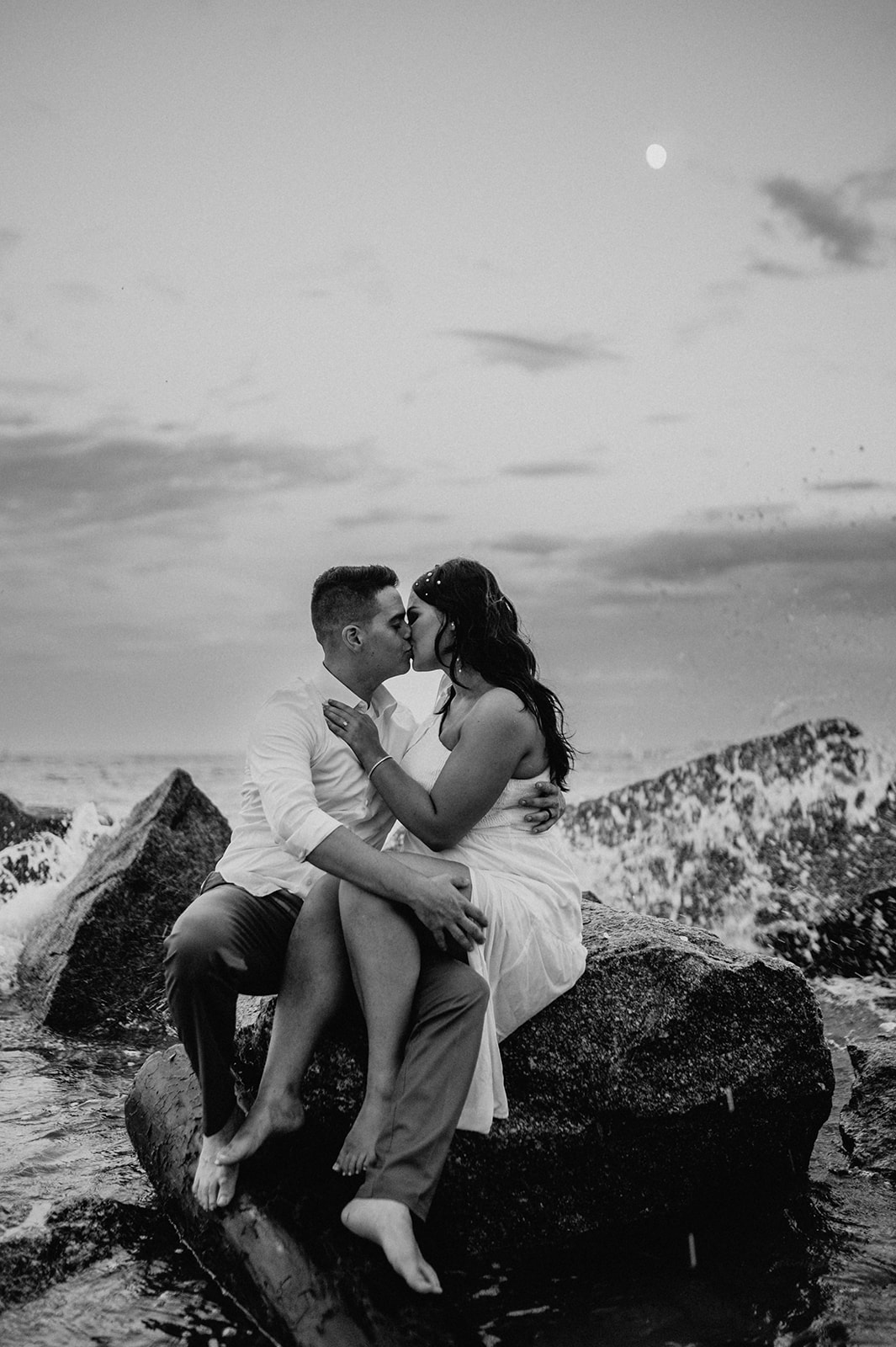 couple sitting at a rock during their moody engagement session 