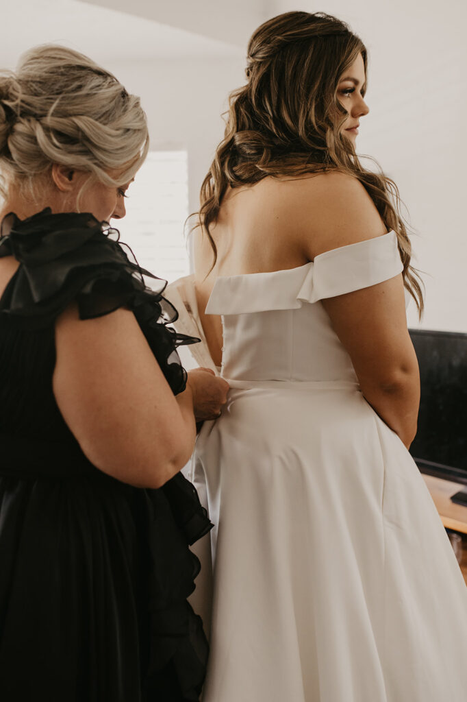 mother of the bride helping her with the wedding dress 
