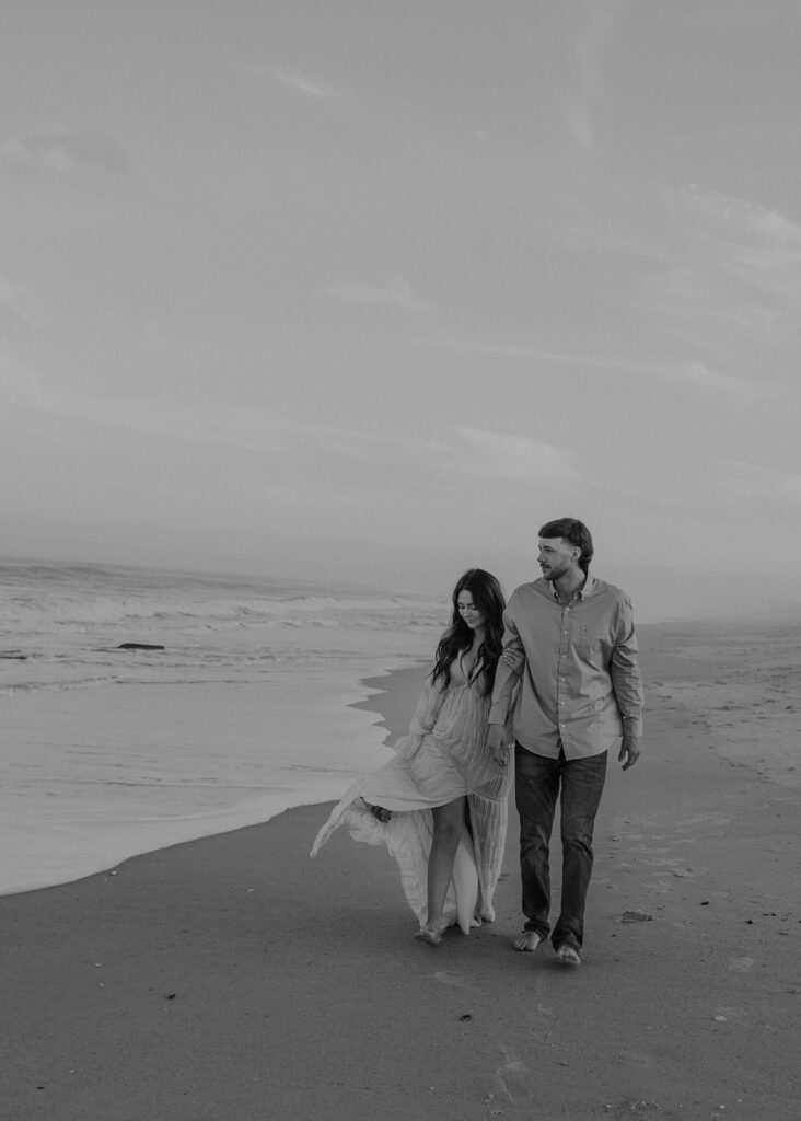 newly engaged couple walking around the beach 