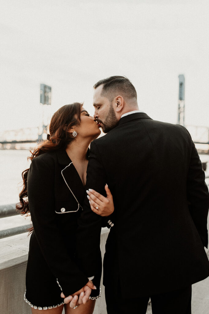 portrait of he newly engaged couple kissing at their timeless downtown engagement session 