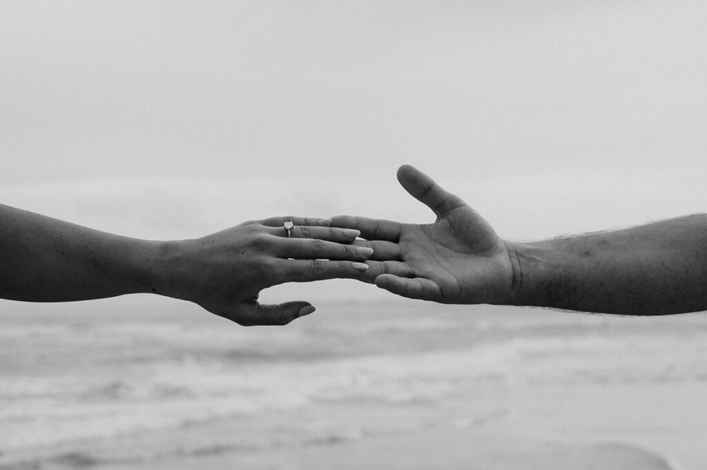 closeup shot of the couple holding hands at their romantic beach proposal 