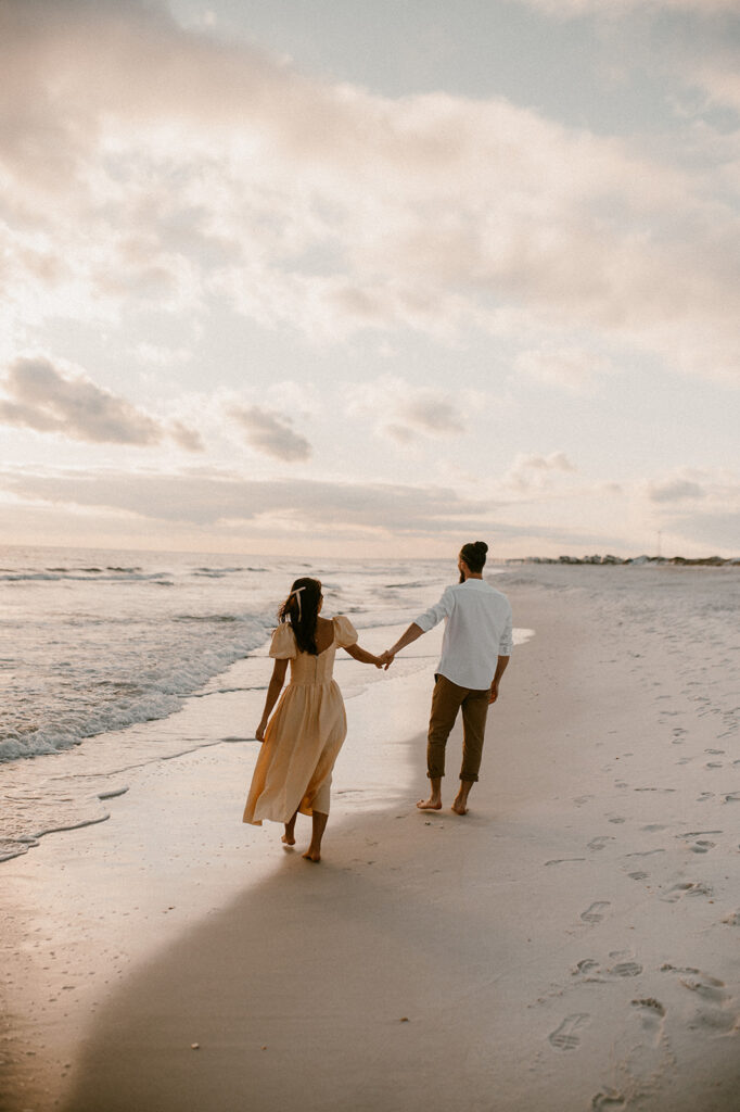 couple holding hands walking around the beach 