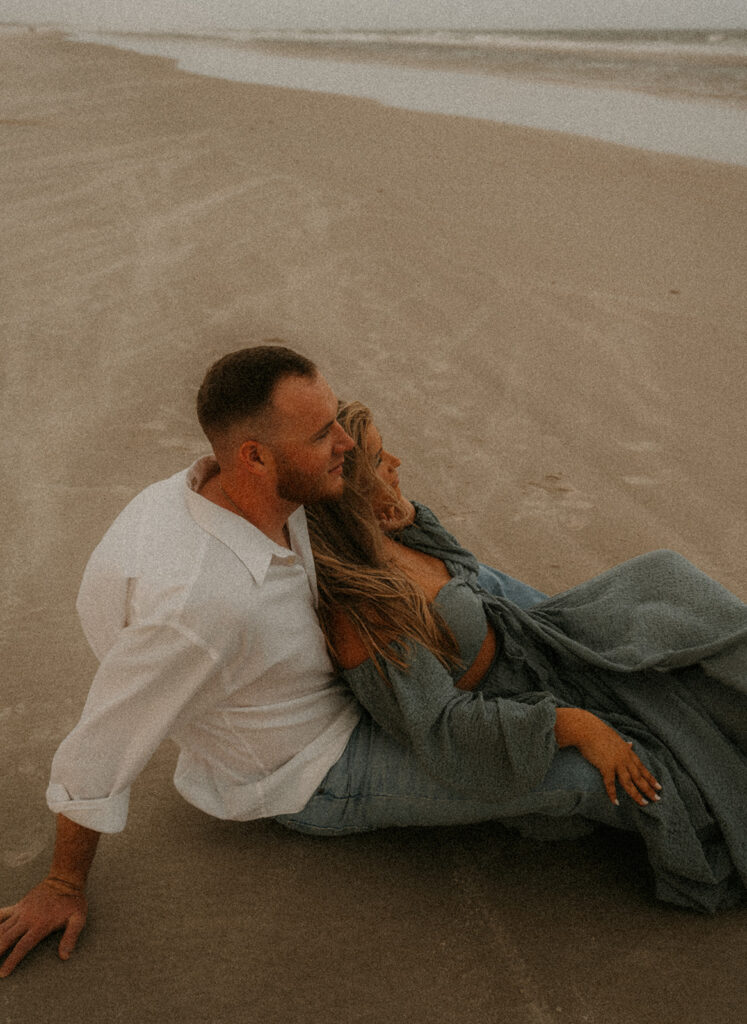 couple sitting at the beach during their engagement session 