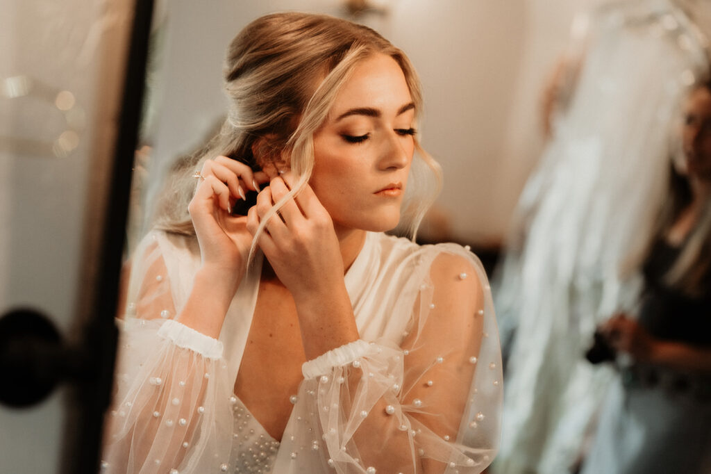 bride putting her jewelry on before the ceremony