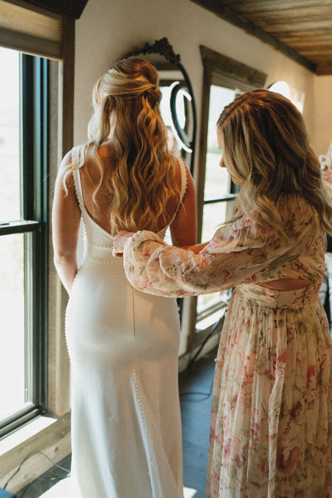 mother of the bride helping her with the wedding dress