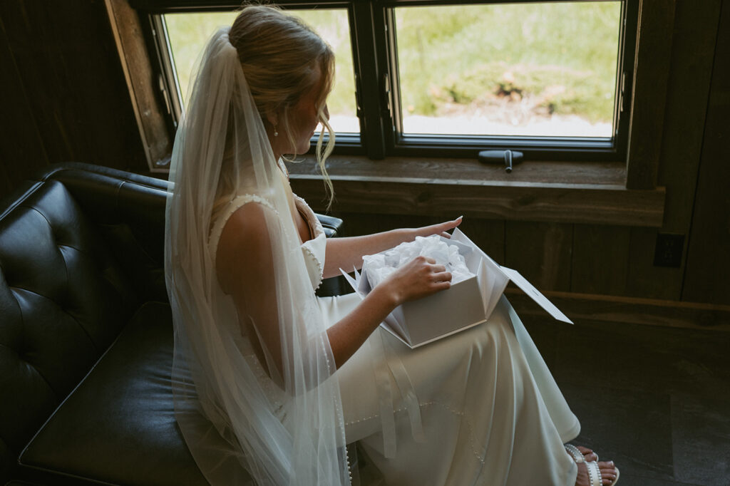 bride opening a gift the groom gave her before the ceremony