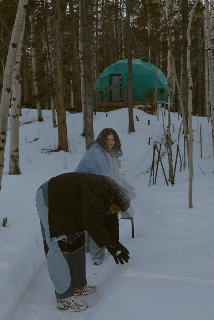 couple playing in the snow during their cozy couple session