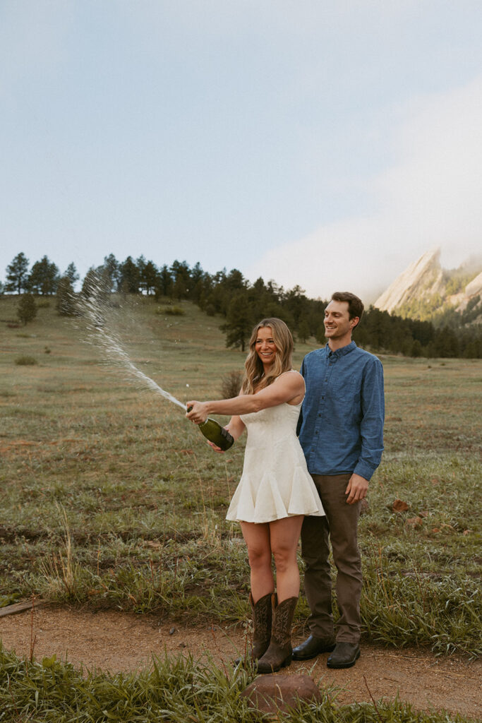 cute couple popping a champagne bottle during their photoshoot