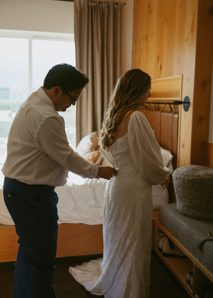 groom helping the bride with her wedding dress
