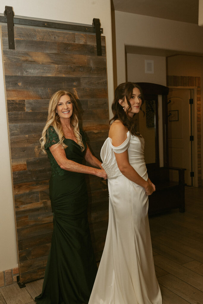mother of the bride helping her with her wedding dress
