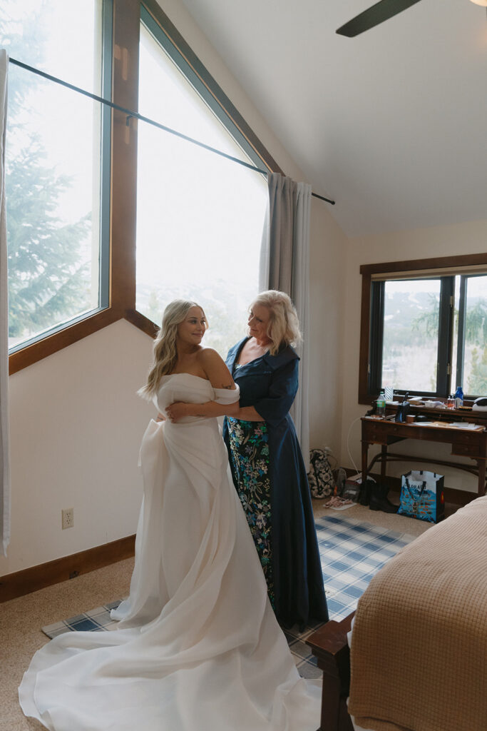 mother of the bride helping her with the wedding dress