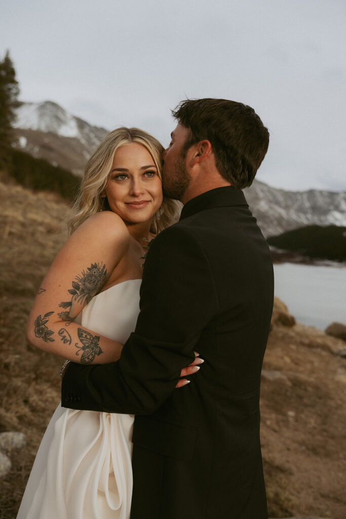 groom kissing the bride on the cheek