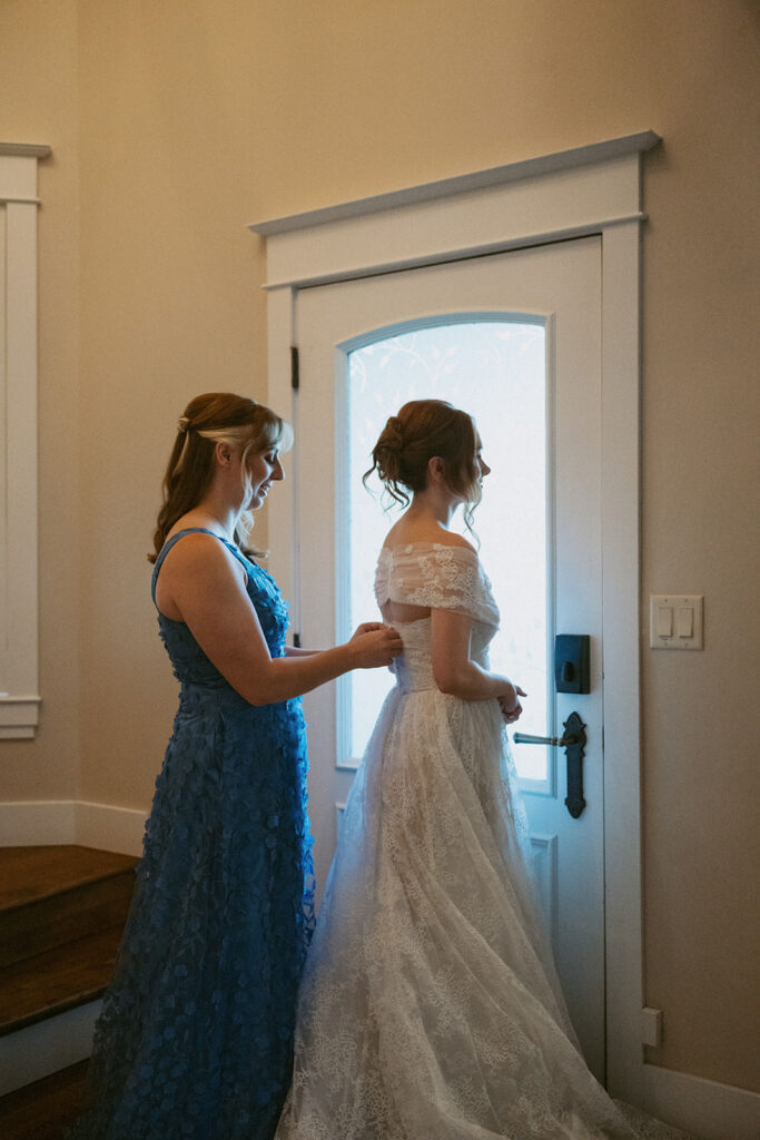 mother of the bride helping her with the wedding dress